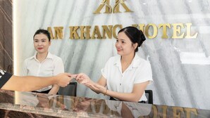 A reception desk with a marble wall and the hotel name 'AN KHANG HOTEL' in gold letters. - An Khang Hotel (Ha Giang 1)