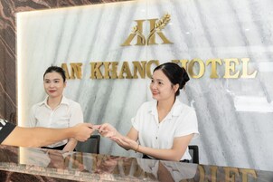Un mostrador de recepción con una pared de mármol y el nombre del hotel 'AN KHANG HOTEL' en letras doradas.