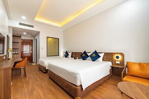 A hotel room with a large bed, a desk, a chair, and a sofa.