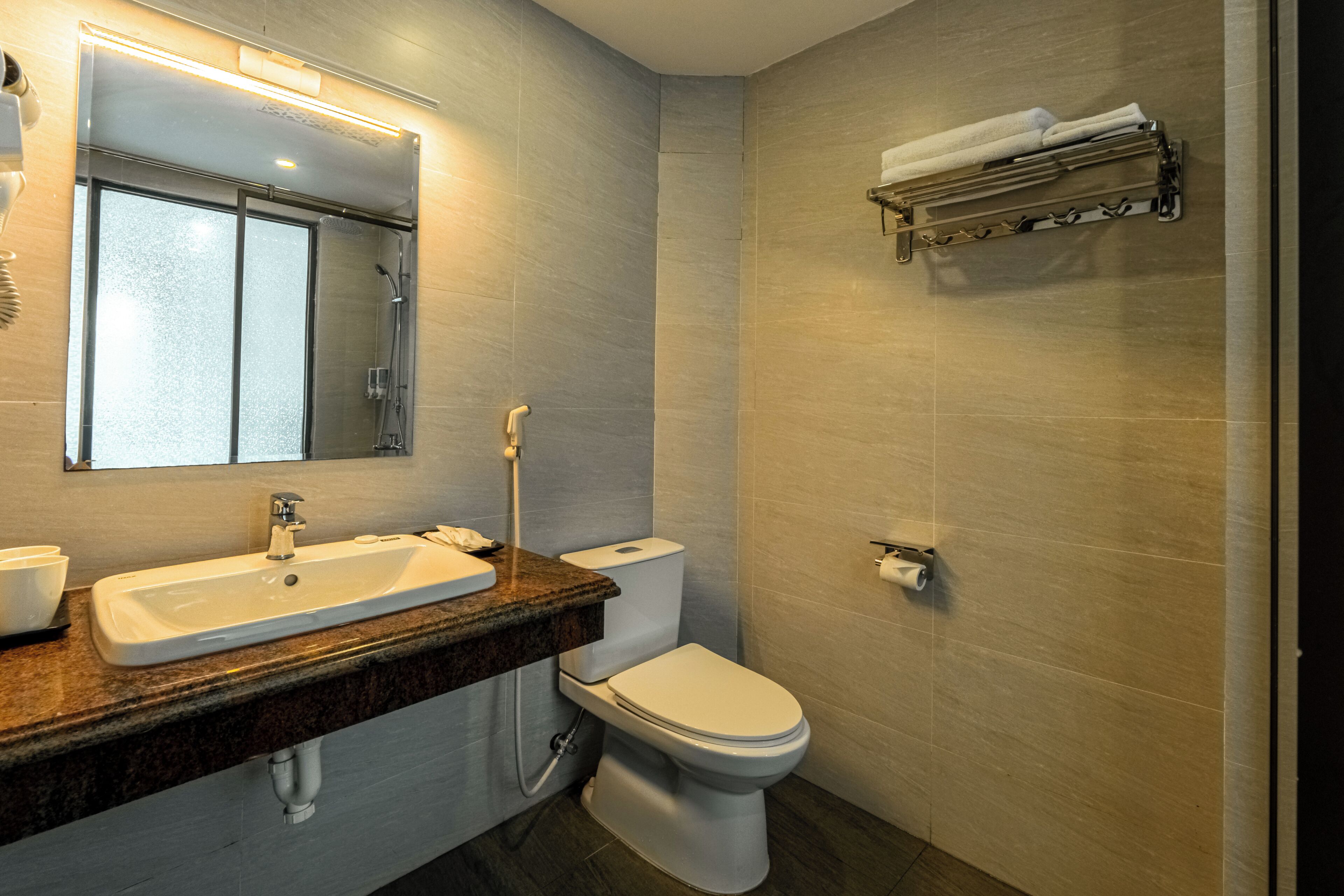 A modern bathroom with a sink, toilet, and a towel rack.