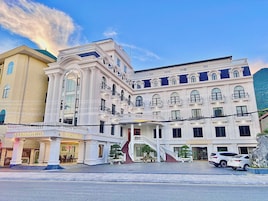 Um hotel com uma entrada imponente, vários andares e uma escadaria que leva à entrada.