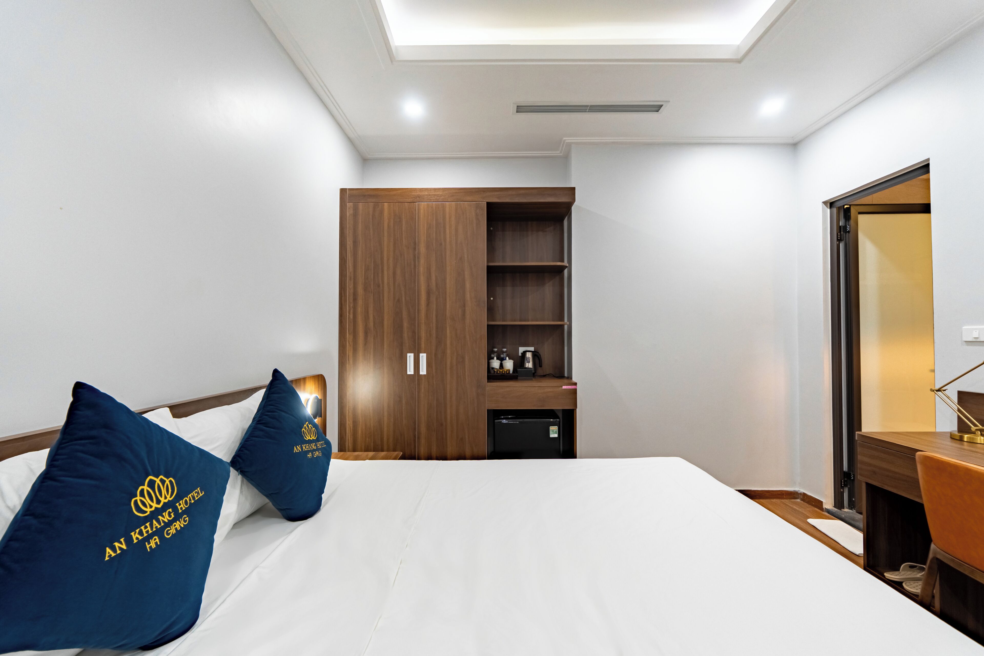 A hotel room with a bed, a wardrobe, a desk, and a mirror.