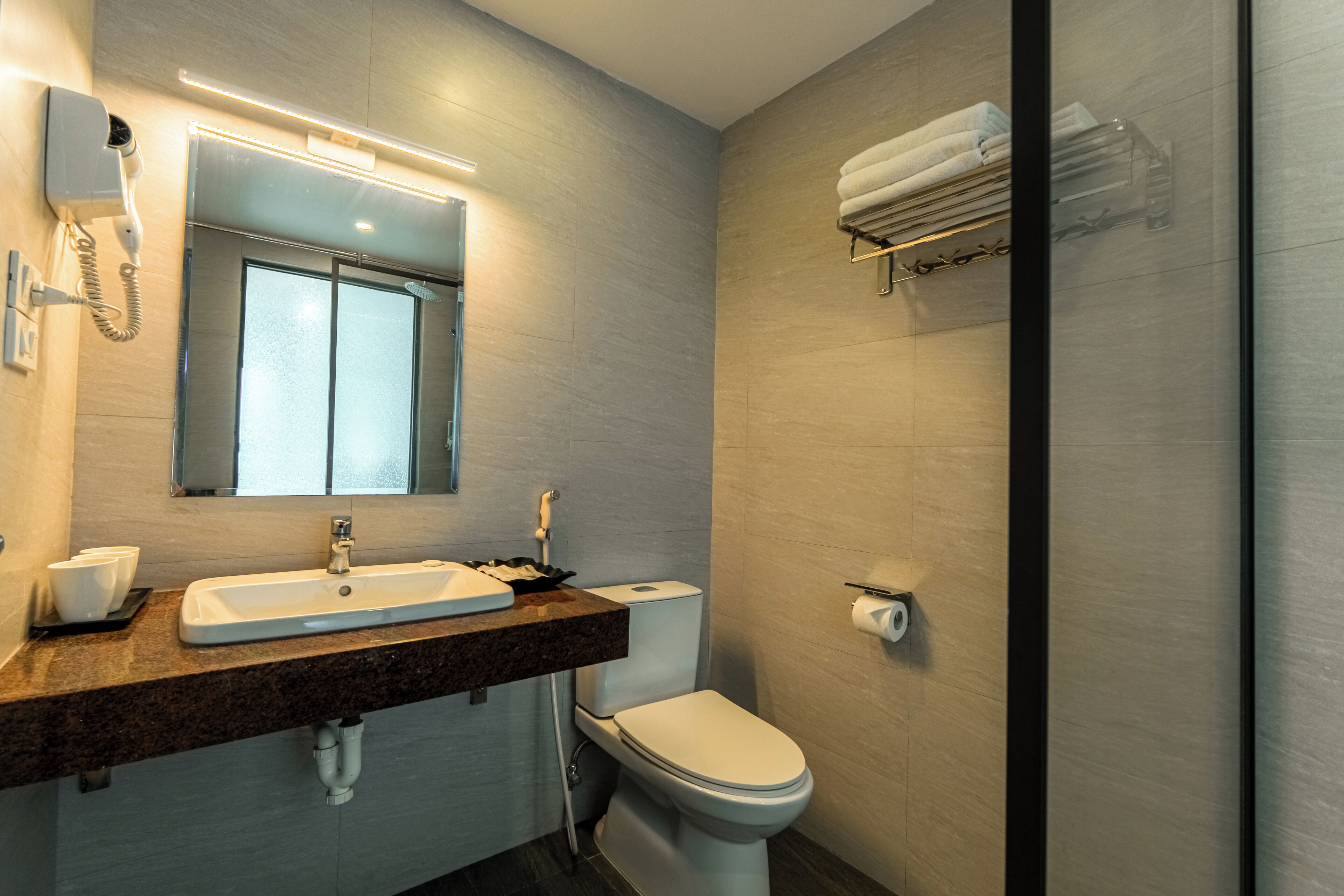 Een moderne badkamer met wastafel, spiegel, toilet en handdoekhouder.