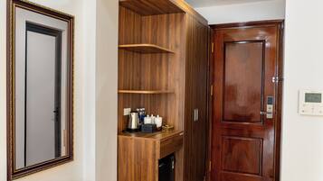 A room with a wooden wardrobe, a mirror, and a door with a digital thermostat.