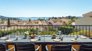 Una terraza con mesa lista para comer, con vista a un pueblo costero y al mar.