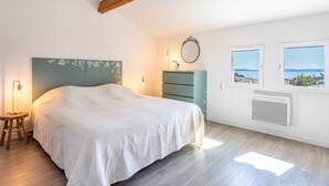 Un dormitorio con cama, cómoda, espejo y ventana con vistas.