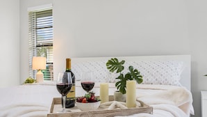 A neatly made bed with a tray of wine, glasses, candles, and a fruit bowl. - Gulf Access Canal home with Pool and Views - Villa Skyline View - Roelens (Cape Coral)