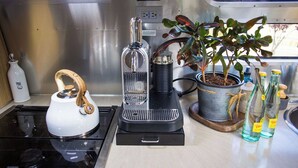 A compact kitchen with a stove, a coffee maker, a kettle, and a potted plant. - Charming Airstream Wellness Retreat in Wine Country (Fairfield)