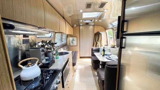 A compact RV kitchen with a stove, sink, and refrigerator. - Charming Airstream Wellness Retreat in Wine Country (Fairfield)