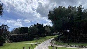 A stone pathway leading through a well-maintained garden with hedges and trees. - Apartment 'Casa Vacanze Ribes' with Sea View, Shared Pool and Private Terrace (olbia)