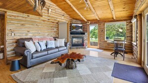A log cabin interior with a fireplace, a sofa, a coffee table, and a dining area. - Sale- Golf Course Getaway-Message for Discount on 2 courses on property (Lima)