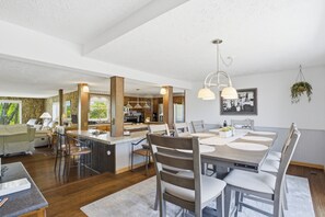 A spacious kitchen with a central island, a dining area with a large table and chairs, and a living area with a sofa and coffee table.