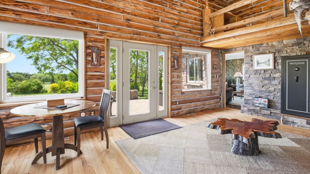 A log cabin interior with a dining area, stone fireplace, and large windows. - Sale- Golf Course Getaway-Message for Discount on 2 courses on property (Lima)