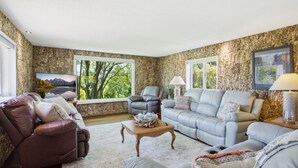 A living room with a stone wall, a leather recliner, a grey sofa, and a wooden coffee table. - Sale- Golf Course Getaway-Message for Discount on 2 courses on property (Lima)
