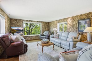 A living room with a stone wall, a leather recliner, a grey sofa, and a wooden coffee table.