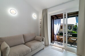 Ein modernes Wohnzimmer mit einer Couch, einem Balkon mit Tisch und Stühlen sowie einer Schiebeglastür.