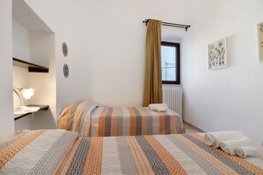 Une chambre d’hôtel avec deux lits, une fenêtre avec un rideau, une table de chevet avec une lampe et des éléments de décoration murale.