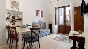 A living room with a dining table, chairs, a sofa, a TV, and a door leading outside. - Apartment 'Unit 1' with Shared Terrace, Wi-Fi and Air Conditioning (Rutigliano)