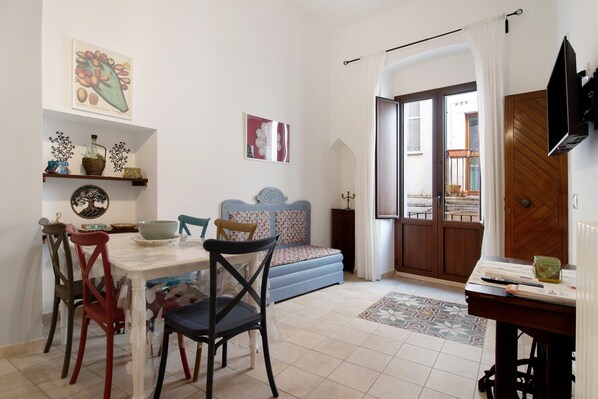 A living room with a dining table, chairs, a sofa, a TV, and a door leading outside. - Apartment 'Unit 1' with Shared Terrace, Wi-Fi and Air Conditioning (Rutigliano)