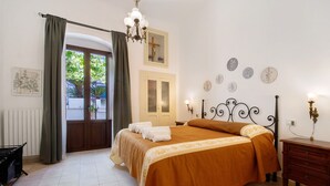 A bedroom with a bed, a dresser, a chandelier, a window with curtains, and a door. - Apartment 'Unit 1' with Shared Terrace, Wi-Fi and Air Conditioning (Rutigliano)