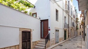 A narrow street with buildings on either side, a wooden door, and a metal gate. - Apartment 'Unità Due' with Shared Terrace, Wi-Fi, and Air Conditioning (Rutigliano)