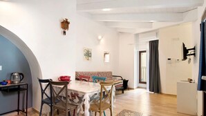 A dining area with a table, chairs, a sofa, a clock, and a refrigerator. - Apartment 'Unità Due' with Shared Terrace, Wi-Fi, and Air Conditioning (Rutigliano)