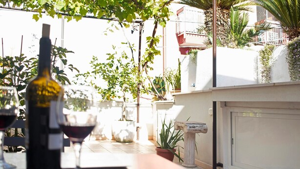 A patio with a wine bottle and glass, potted plants, and a white wall. - Apartment 'Unità Due' with Shared Terrace, Wi-Fi, and Air Conditioning (Rutigliano)