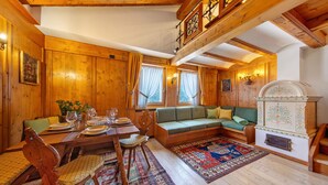 A wooden interior with a dining table set, a sofa, and a fireplace. - Apartment 'Hilde' with Mountain View, Private Terrace and Wi-Fi (Peaio)