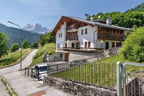A two-story chalet with a balcony, a stone staircase, and a view of mountains. - Apartment 'Hilde' with Mountain View, Private Terrace and Wi-Fi (Peaio)