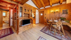 A wooden interior with a dining area, a television, and a fireplace. - Apartment 'Hilde' with Mountain View, Private Terrace and Wi-Fi (Peaio)