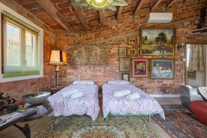 A room with two beds, a large painting, a lamp, and a rustic brick wall. - Apartment 'La Fabriqueta Deluxe' with Mountain View, Wi-Fi and Air Conditioning (Riudecanyes)