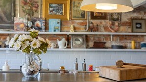 A kitchen counter with a vase of flowers, a wooden cutting board, and various kitchen items. - Apartment 'La Fabriqueta Deluxe' with Mountain View, Wi-Fi and Air Conditioning (Riudecanyes)