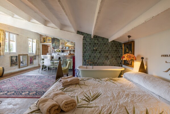 Un dormitorio con una cama grande, una bañera y una zona de comedor con vistas.