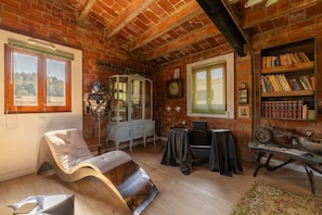 A room with exposed brick walls, a vintage armchair, a bookshelf, and a small table with a radio. - Apartment 'La Fabriqueta Deluxe' with Mountain View, Wi-Fi and Air Conditioning (Riudecanyes)