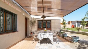 An outdoor patio with a table and chairs, a hanging light fixture, and potted plants. - Apartment 'La Fabriqueta Deluxe' with Mountain View, Wi-Fi and Air Conditioning (Riudecanyes)