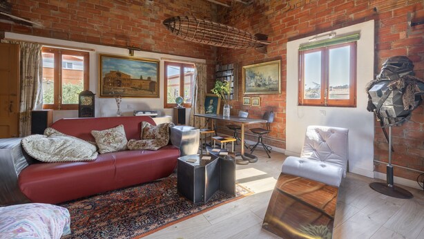 A cozy living room with a red sofa, a coffee table, a dining table, and a brick wall. - Apartment 'La Fabriqueta Deluxe' with Mountain View, Wi-Fi and Air Conditioning (Riudecanyes)