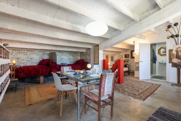 A dining area with a glass table, chairs, and a red sofa.