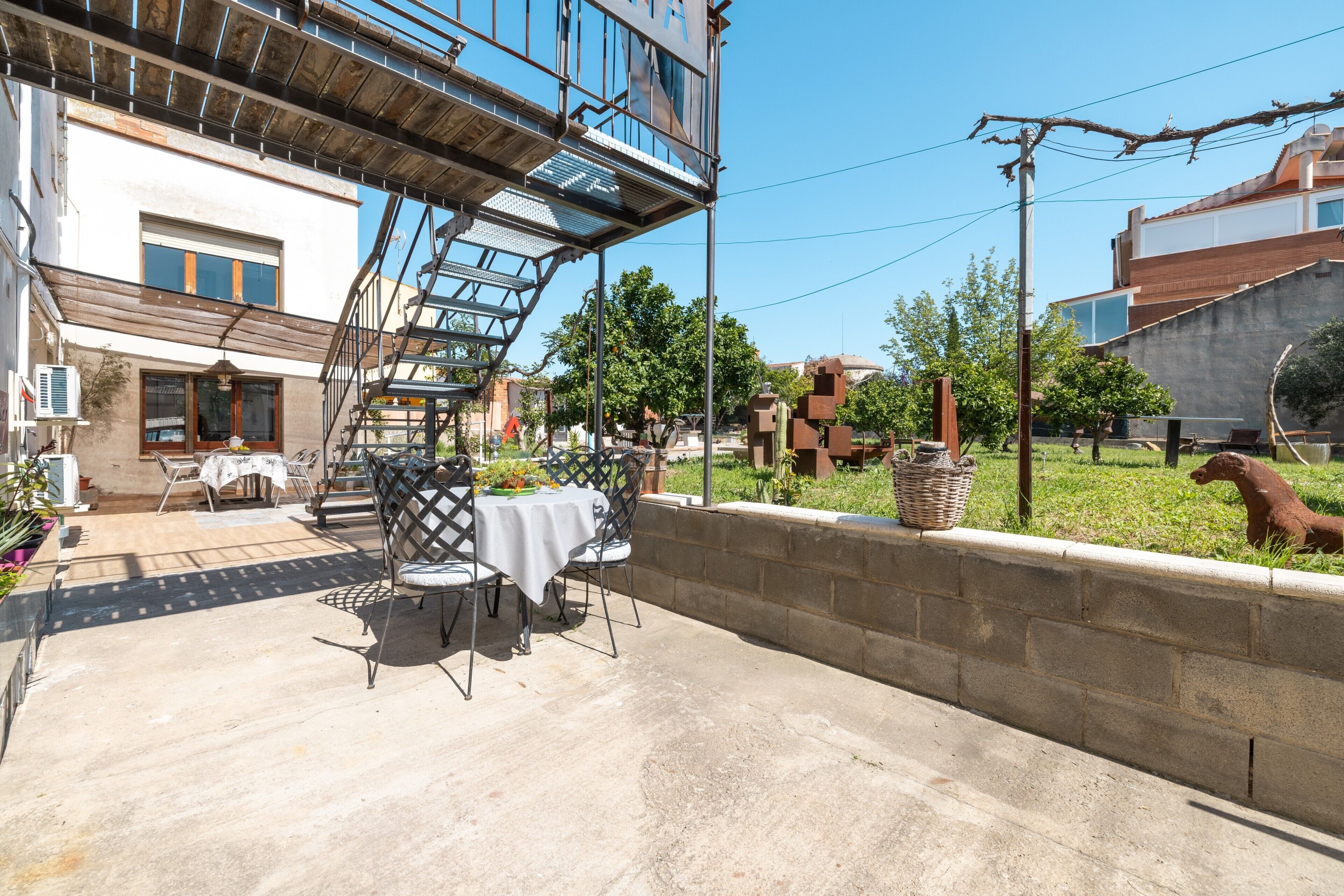 A courtyard with a table and chairs, a staircase, and a view of surrounding buildings.
