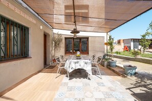 An outdoor patio with a table and chairs, a hanging light fixture, and potted plants.