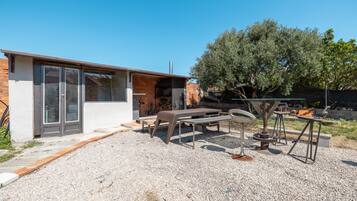 A modern outdoor patio with a brick building, a table, chairs, and a pergola.
