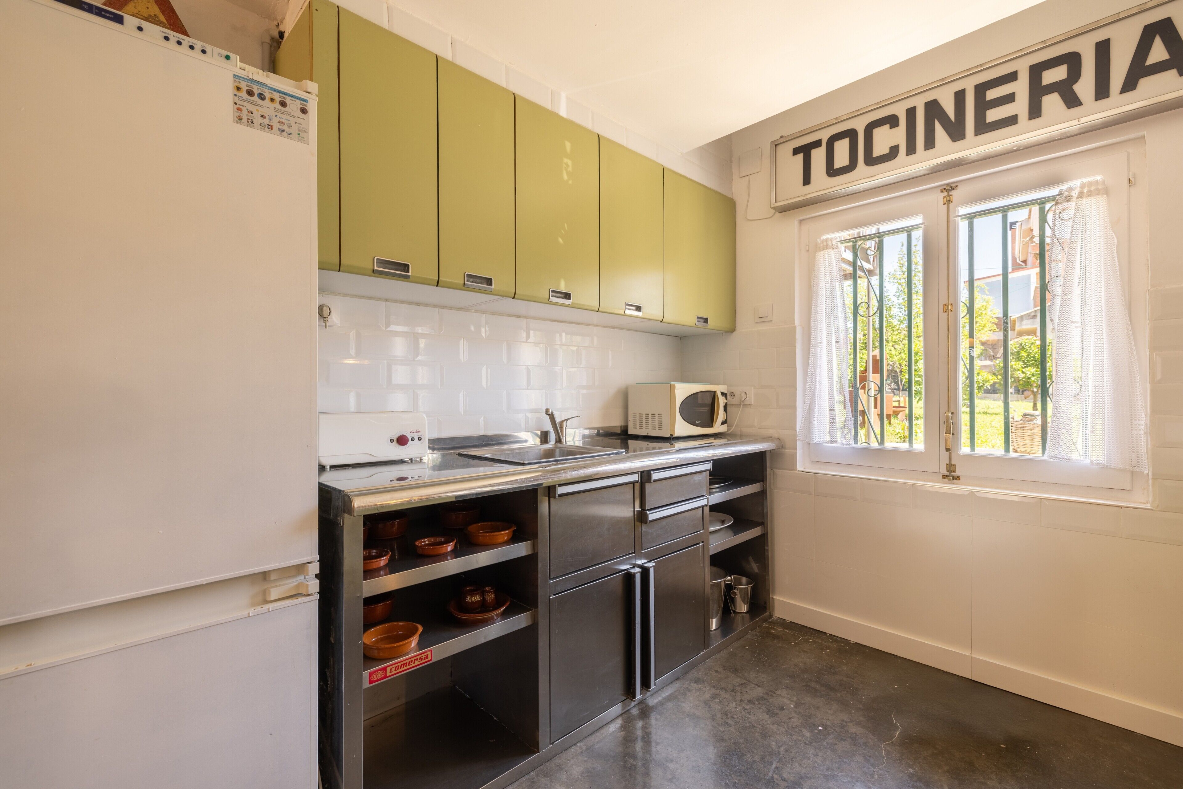 A kitchen with green cabinets, a microwave, and a sink.