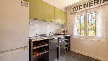 A kitchen with green cabinets, a microwave, and a sink.