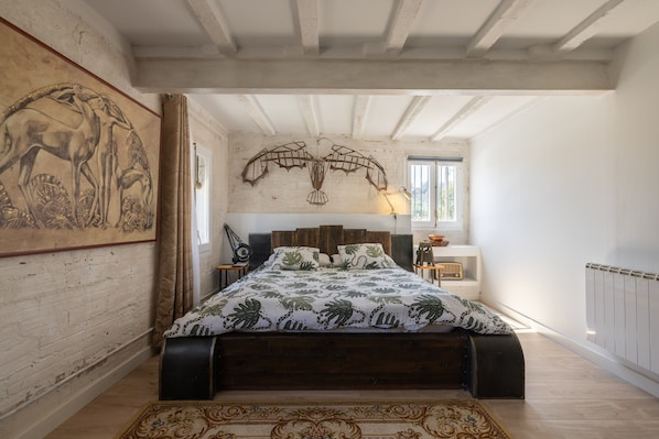 Un dormitorio con una cama de madera, un cuadro grande en la pared, una lámpara y una ventana.