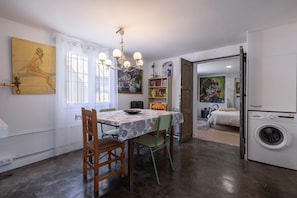 Un comedor con una mesa, sillas, una araña y un cuadro en la pared.