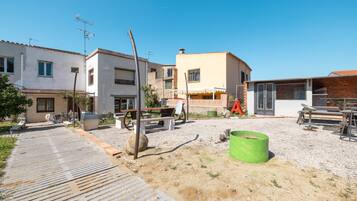 A residential area with houses, a gravel driveway, and outdoor furniture.