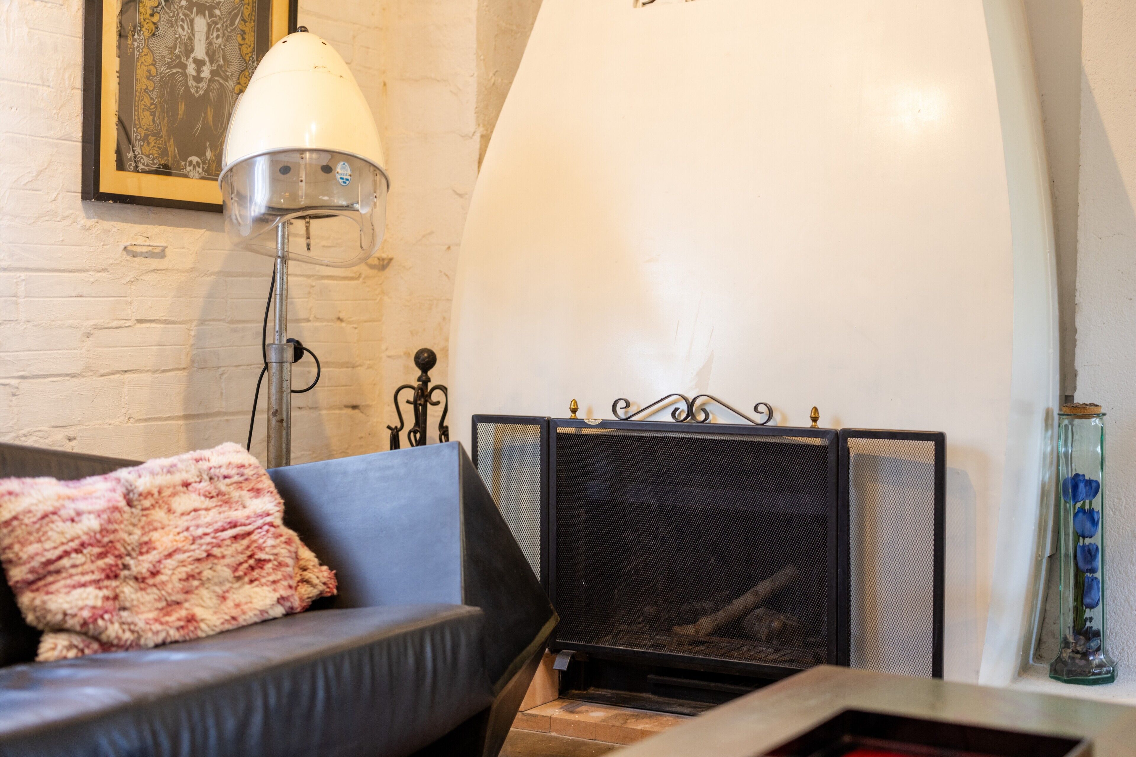 A room with a fireplace, a sofa with a throw blanket, a floor lamp, and a framed picture on the wall.