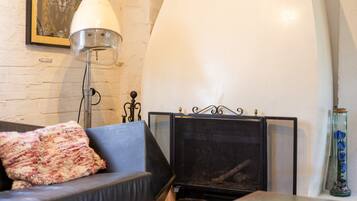 A room with a fireplace, a sofa with a throw blanket, a floor lamp, and a framed picture on the wall.