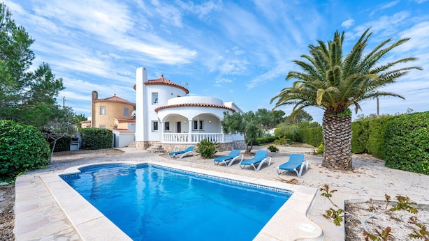 A swimming pool with lounge chairs, a palm tree, and a building with a red-tiled roof. - Villa 'Flor' with sea views, private pool and Wi-Fi (Les Tres Cales)