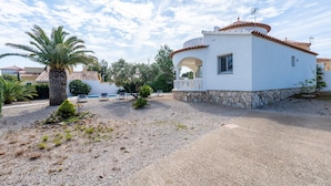 A white building with a stone base, a tiled roof, and a small porch. - Villa 'Flor' with sea views, private pool and Wi-Fi (Les Tres Cales)