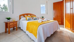 A bedroom with a bed, a nightstand, a wardrobe, and a window. - Villa 'Flor' with sea views, private pool and Wi-Fi (Les Tres Cales)